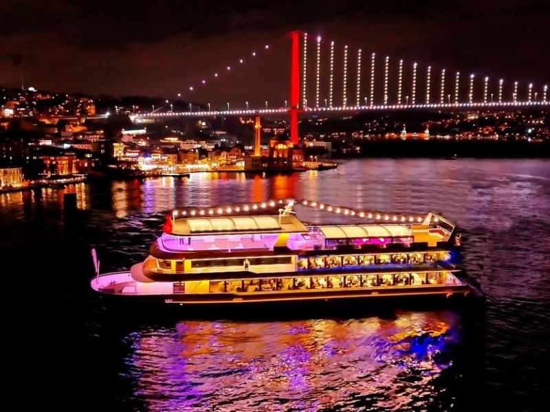 Istanbul bei Nacht mit beleuchtetem Schiff und Brücke im Hintergrund